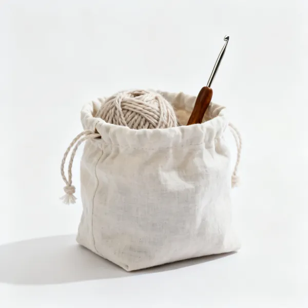 A fabric drawstring project bag with yarn and a crochet hook inside