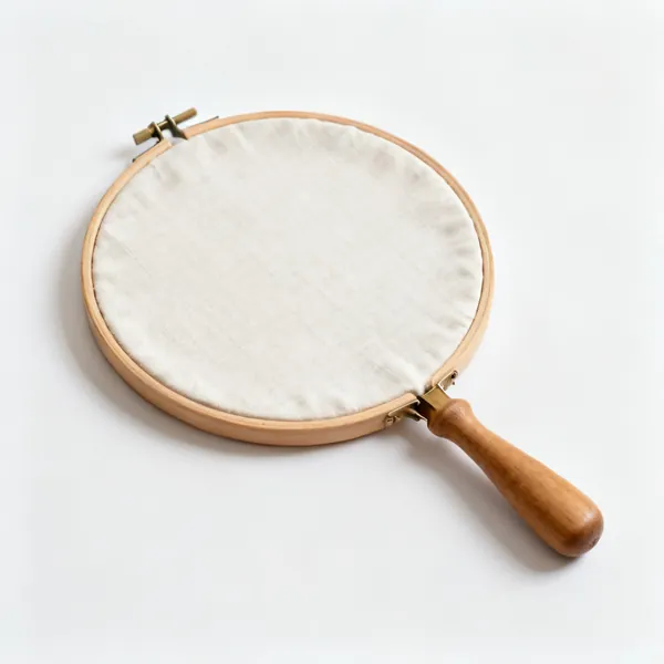A wooden embroidery hoop with fabric stretched in it